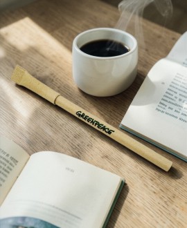 Bolígrafo ecológico de cartón reciclado junto a taza de café y libro