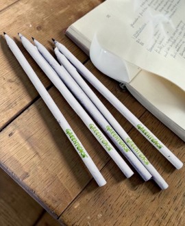Lápices ecológicos blancos junto a libro abierto sobre mesa de madera
